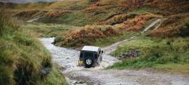 A Land Rover defender drives through a river deep in the Scottish countryside