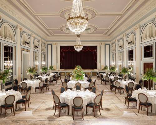 A ballroom with chandeliers set up with round tables for a large dinner