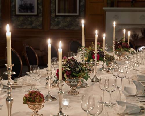 A candle lit silver service on a large table in the billiard room