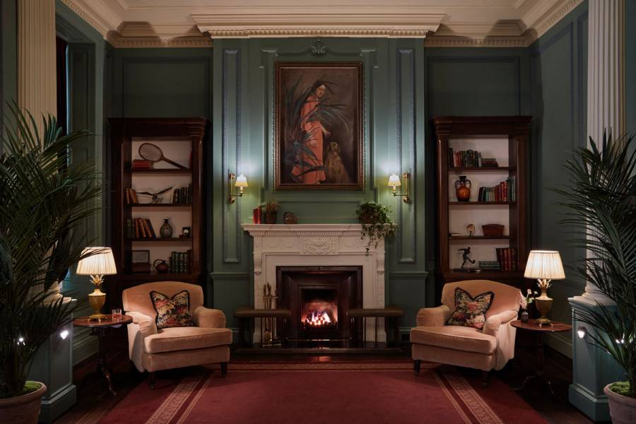 Two arm chairs sit next to an open fire in the ornate parlour room at Gleneagles