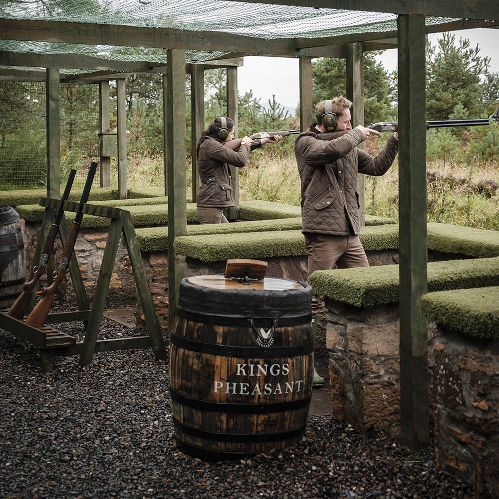 A man and woman shoot clays on a range