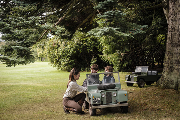 A young instructor shows a child how to drive a min Land Rover replica