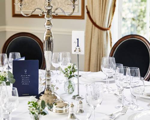 A table laid for silver service with silver candelabra in the drawing room