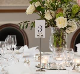 a table laid for silver service with large flower arrangement