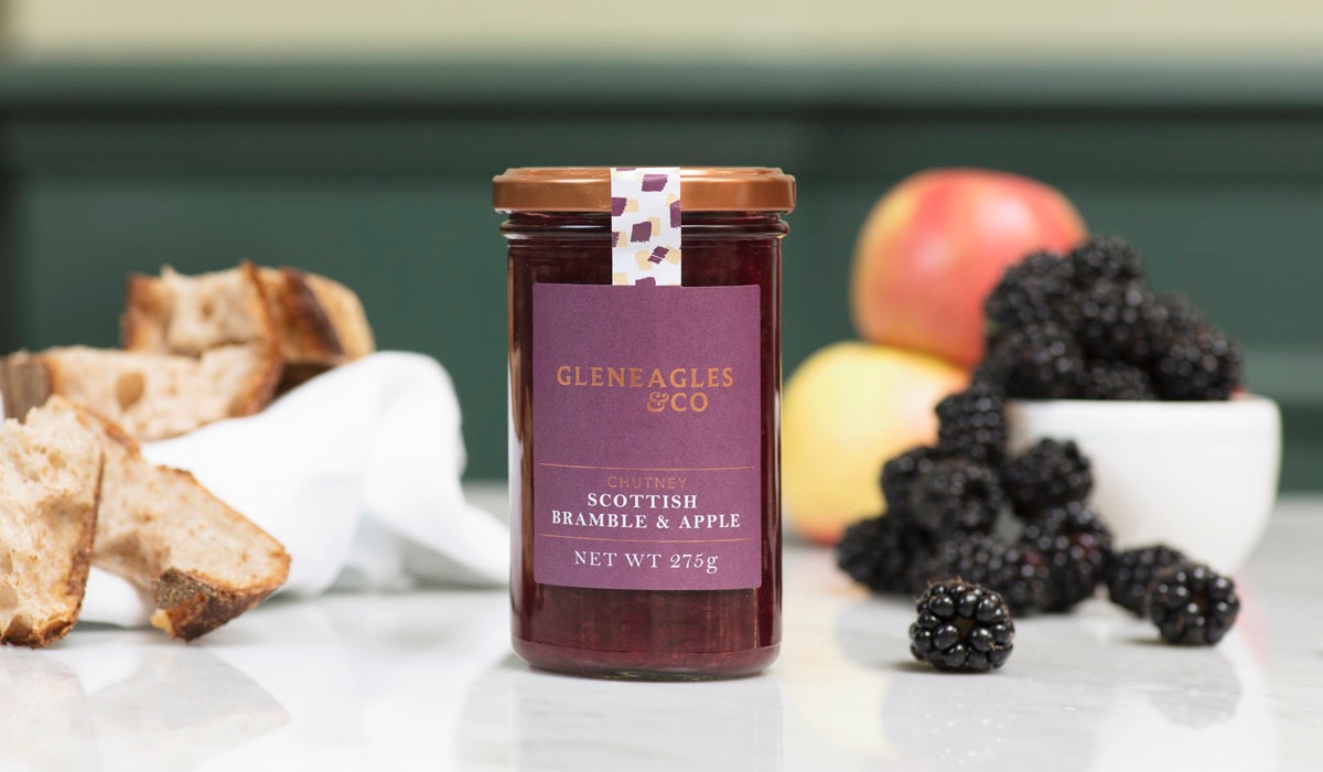 A jar of jam with fruit surrounding it