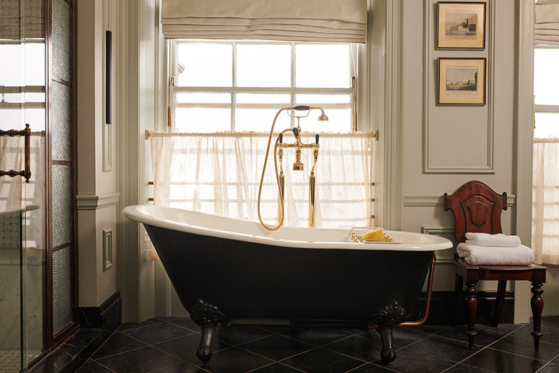 A large free-standing rollmop bath with gold taps and shower head