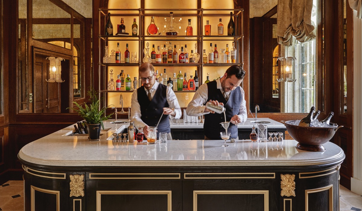 Two barmen serve drinks in the bar of the drawing room at Gleneagles