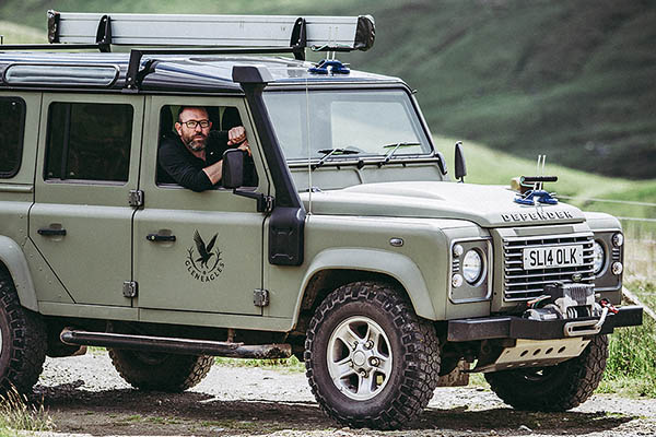 A man looks out into the distance from the window of a land rover defender