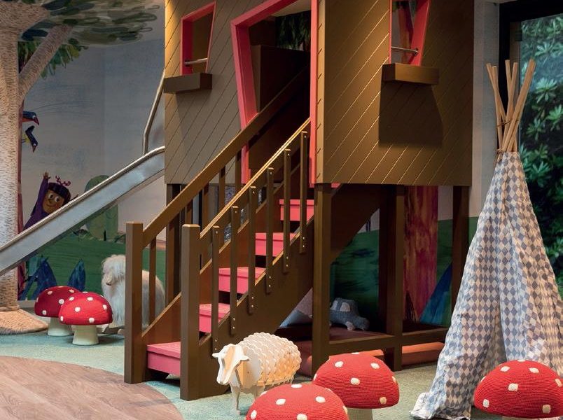 A large tree-house shaped climbing frame with mushroom shaped stools and kids toys