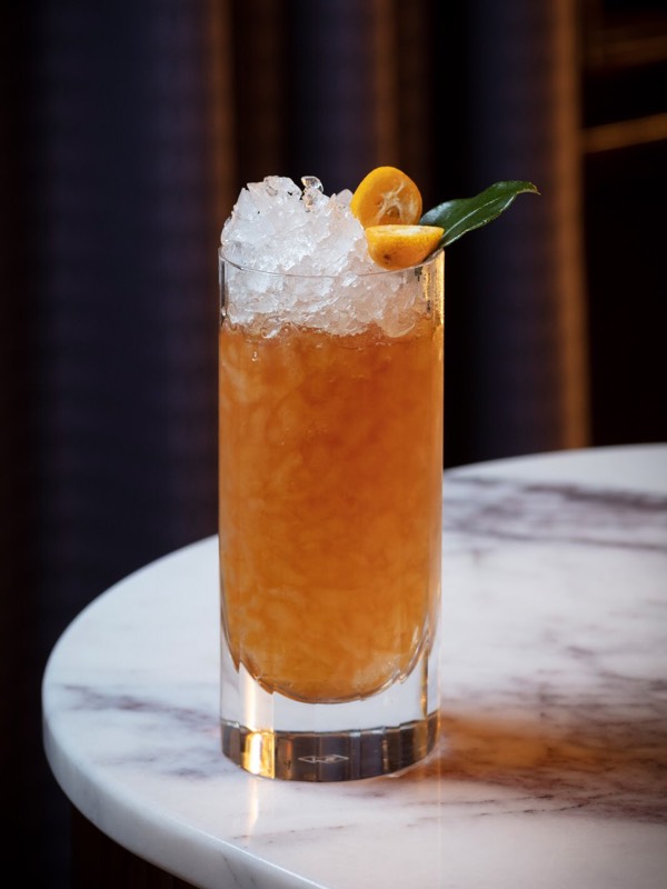 A bright orange cocktail. filled with ice on a marble worktop