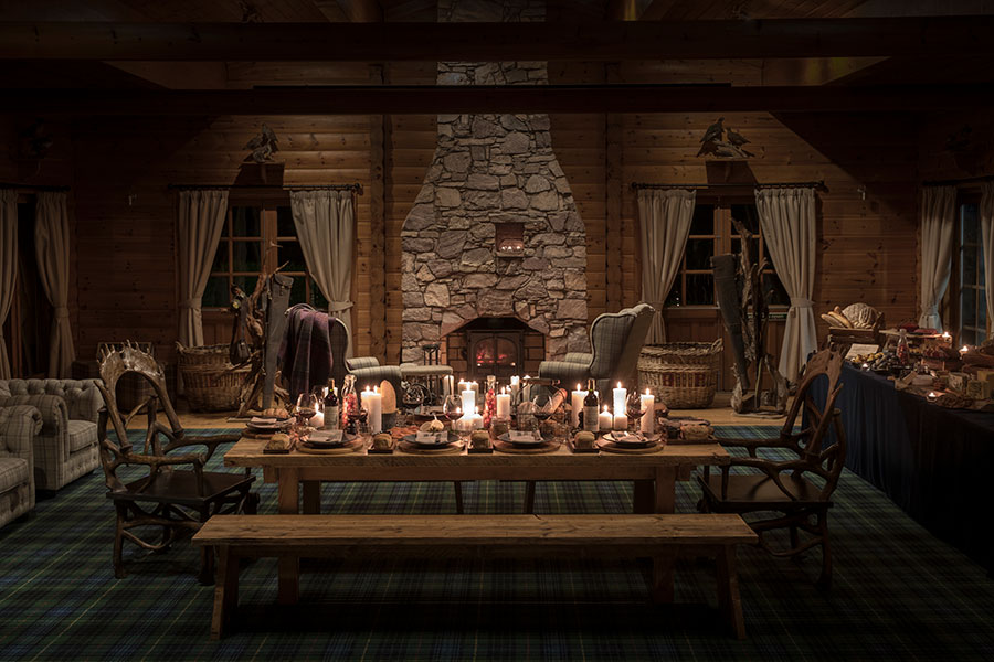 An atmospherically lit shooting lodge set for a private dinner at night