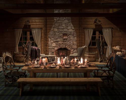 An atmospherically lit shooting lodge set for a private dinner at night