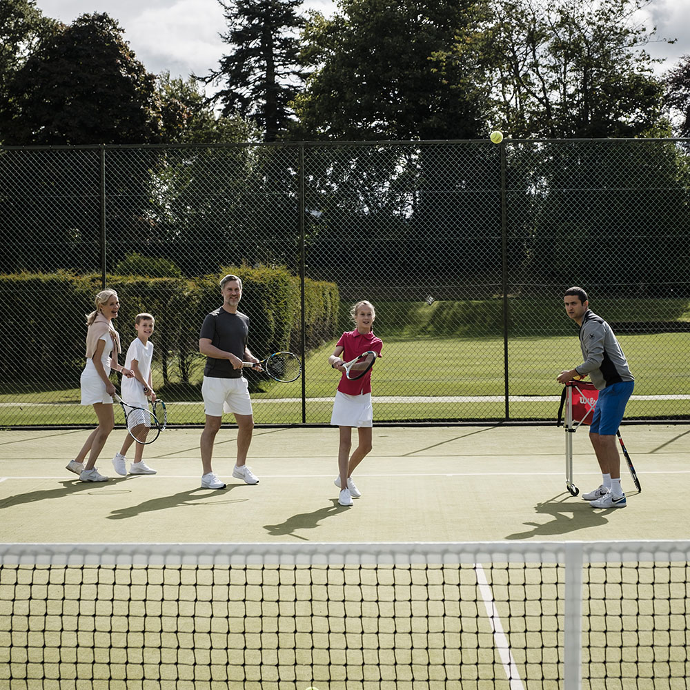 A family enjoy a tennis lesson with a coach