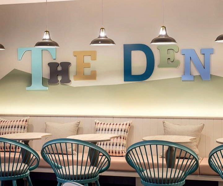 A big sign saying 'the den' with tables and seating for children