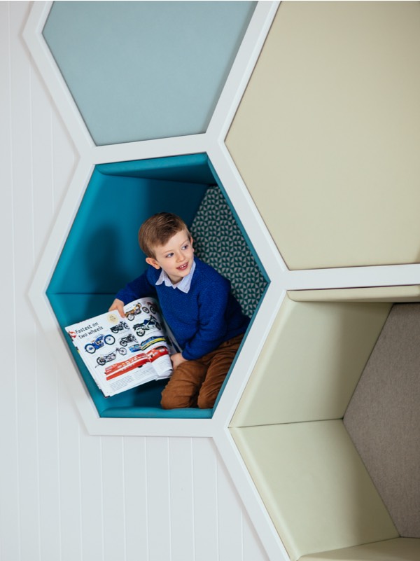 A boy holds up something he painted in the Den