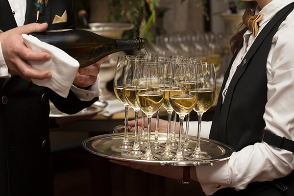 Two waiters pour a tray full of champagne flutes