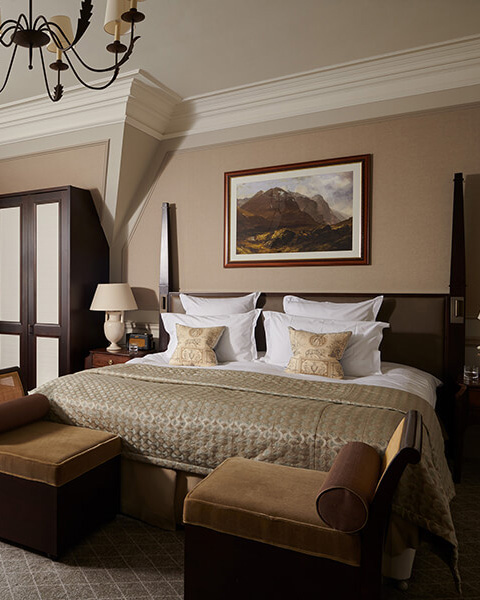 A king sized bed in luxury 5 star accommodation with a mountain landscape painting above it