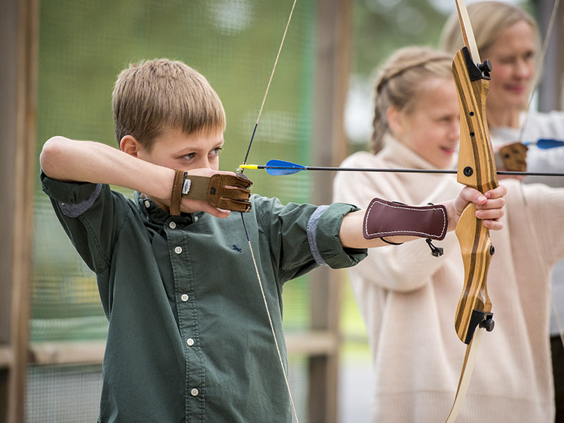 A boy pulling the string of an archer's bow
