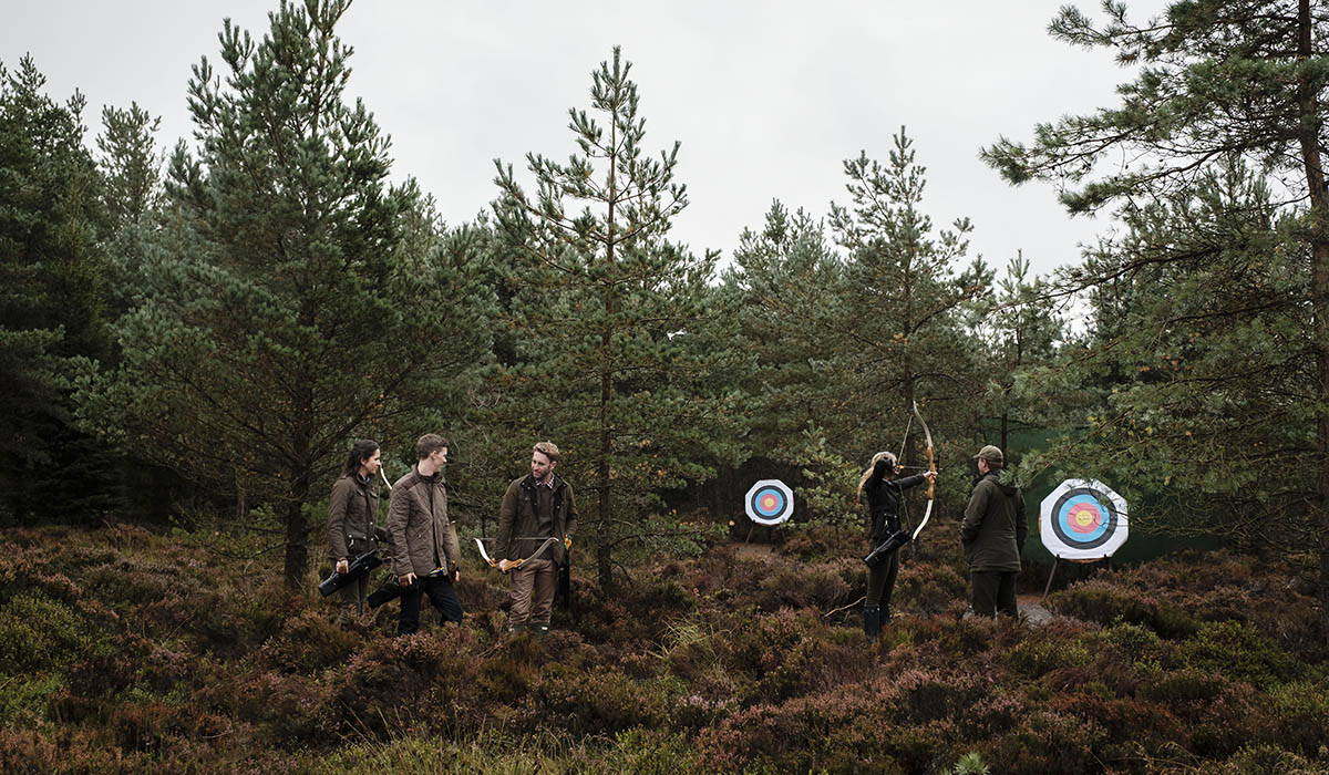 A group of people in woodland near Gleneagles doing archery