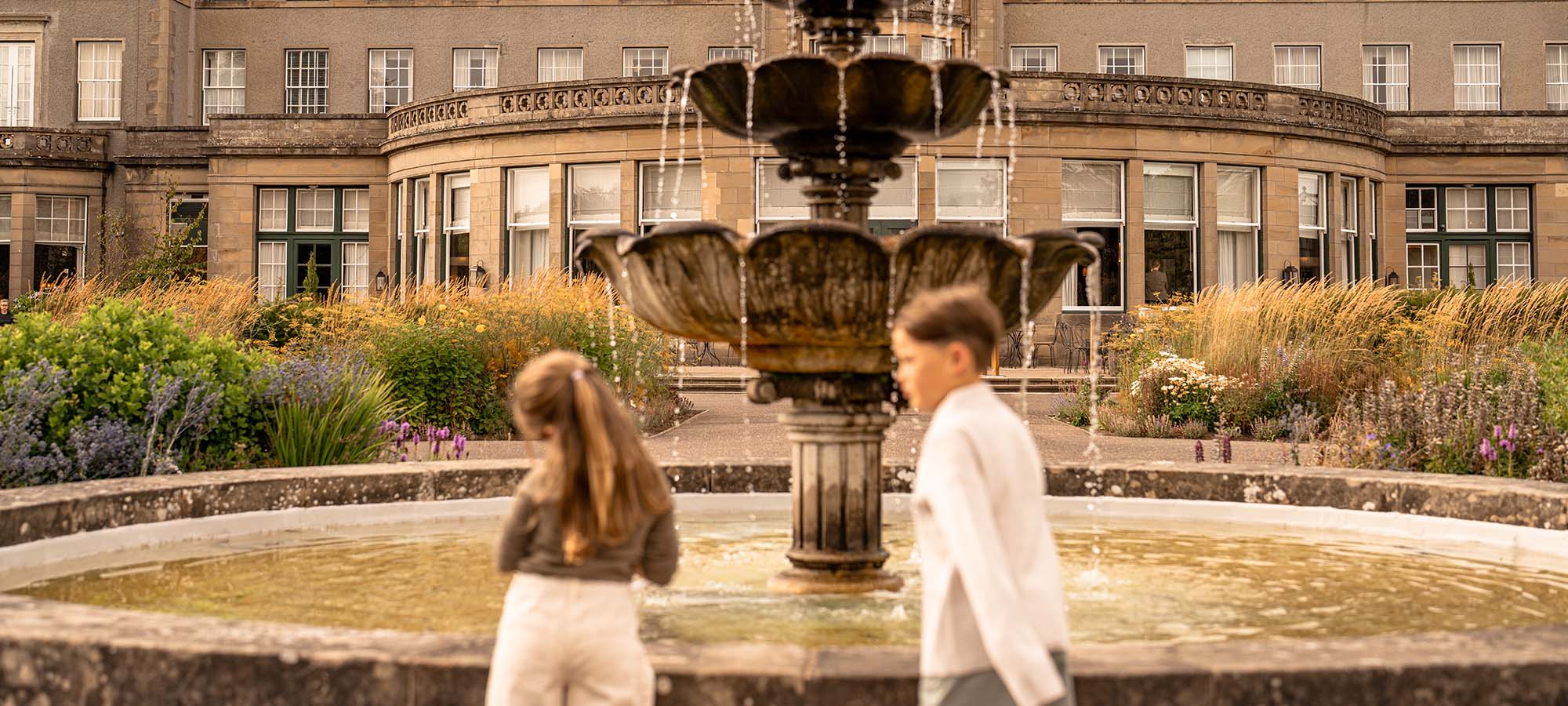 Children playing beside fountain in landscaped gardens