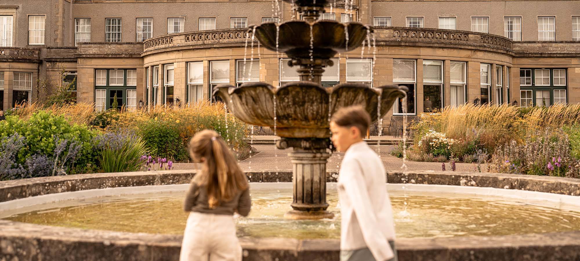 Children playing beside fountain in landscaped gardens