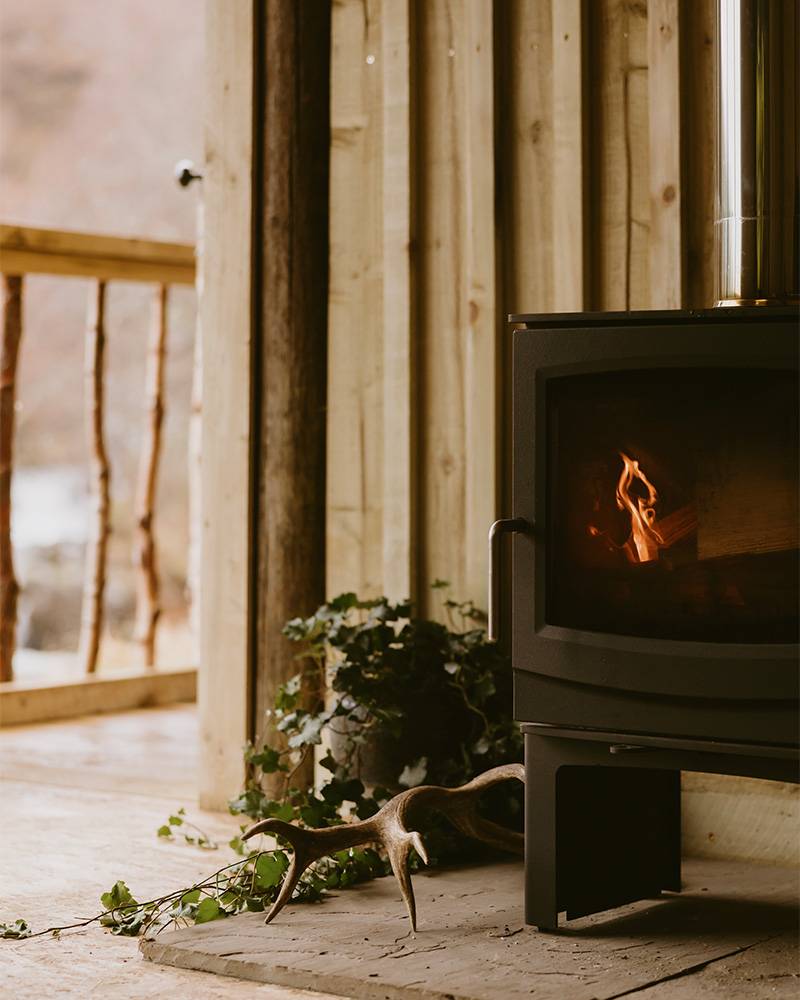 Cosy fire setting with wooden cladding in background at High Moor Lodge