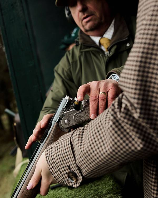 Man coaching woman on holding gun at Gleneagles shooting lodge